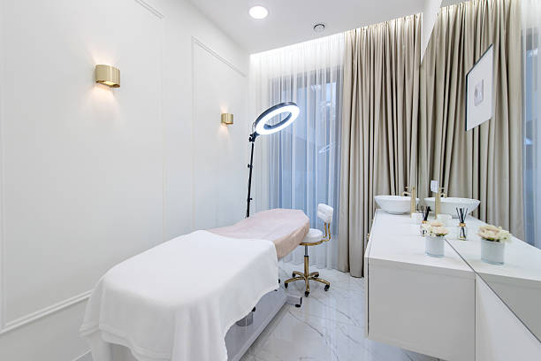 Elegant and minimalistic spa room interior with a treatment table, a ring light, and a serene ambiance.